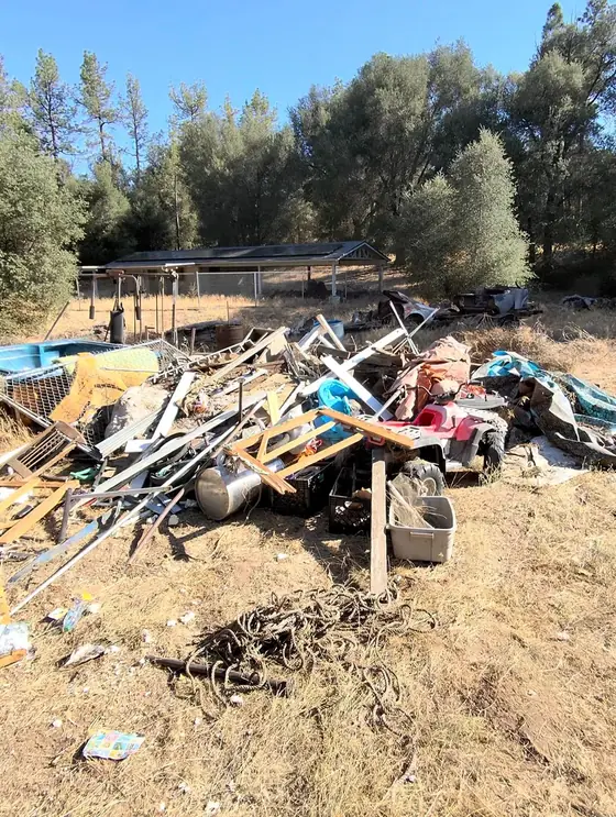 A yard piled with scrap timber, furniture and household junk before the cleanout