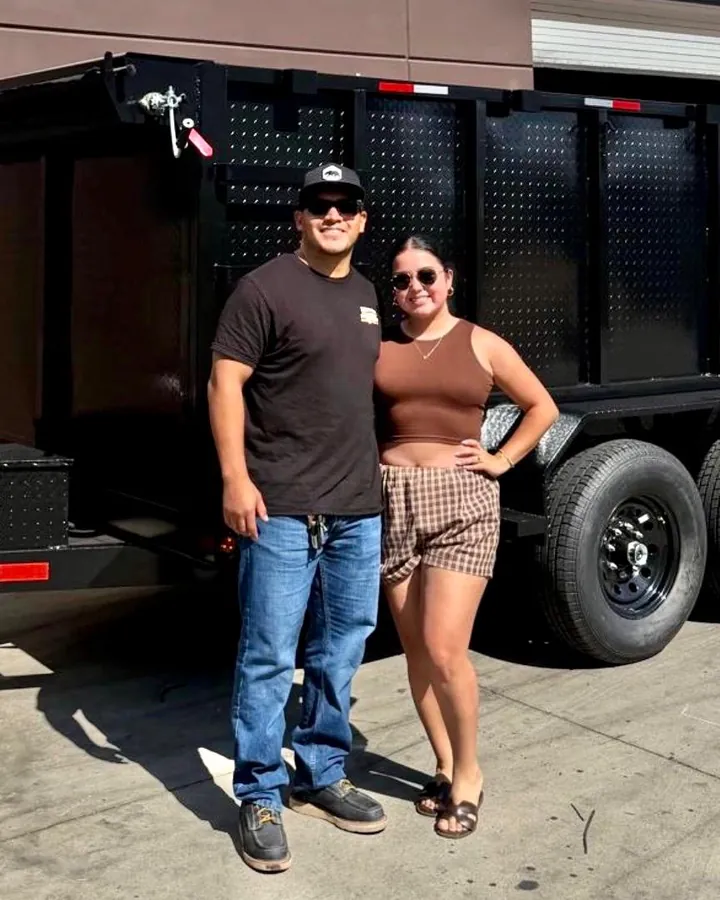 Jose Redona, founder of Topline Junk Haulers, with his wife in front of the company hauling trailer