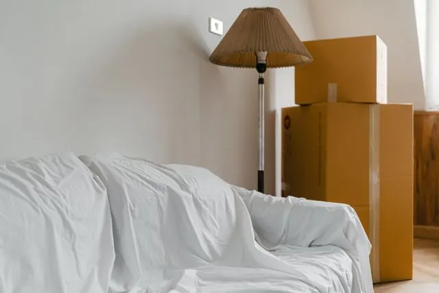 Sheet-covered furniture and stacked moving boxes ready to be hauled away